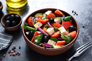 Classic Greek salad with feta and olives on a concrete background.