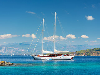 Fototapeta na wymiar alone white sail yacht in emerald lagoon in summer day in Turkey