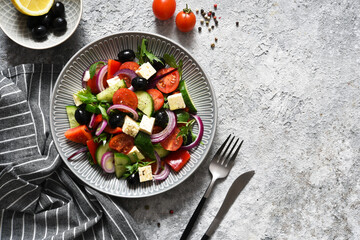 Classic Greek salad with feta and olives on a concrete background.