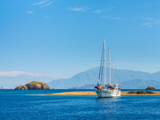Fototapeta na wymiar beautiful white sail yacht on the beach under blue sky in Turkey with copy space