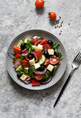 Classic Greek salad with feta and olives on a concrete background.