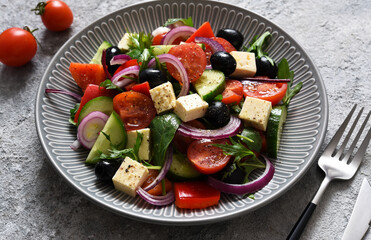Classic Greek salad with feta and olives on a concrete background.