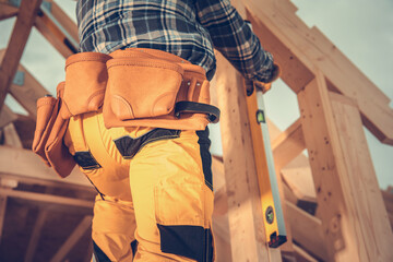 Contractor Using Spirit Level While Building Wooden House Frame