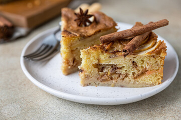 Two pieces of apple pie with cinnamon on a plate, light concrete background. Semolina cake with apple and spices. Homemade mannik.