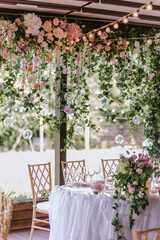 the part of wedding presidium decoration using pink and white flowers, candles, leafs and golden chairs 