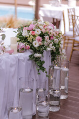 Wedding table decoration of the newlyweds with fresh pink and white flowers and candles.
