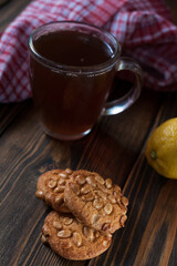Peanut cookies with a mug of tea and lemon on a wooden background. 