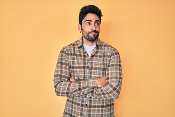 Handsome hispanic man with beard wearing casual clothes smiling looking to the side and staring away thinking.