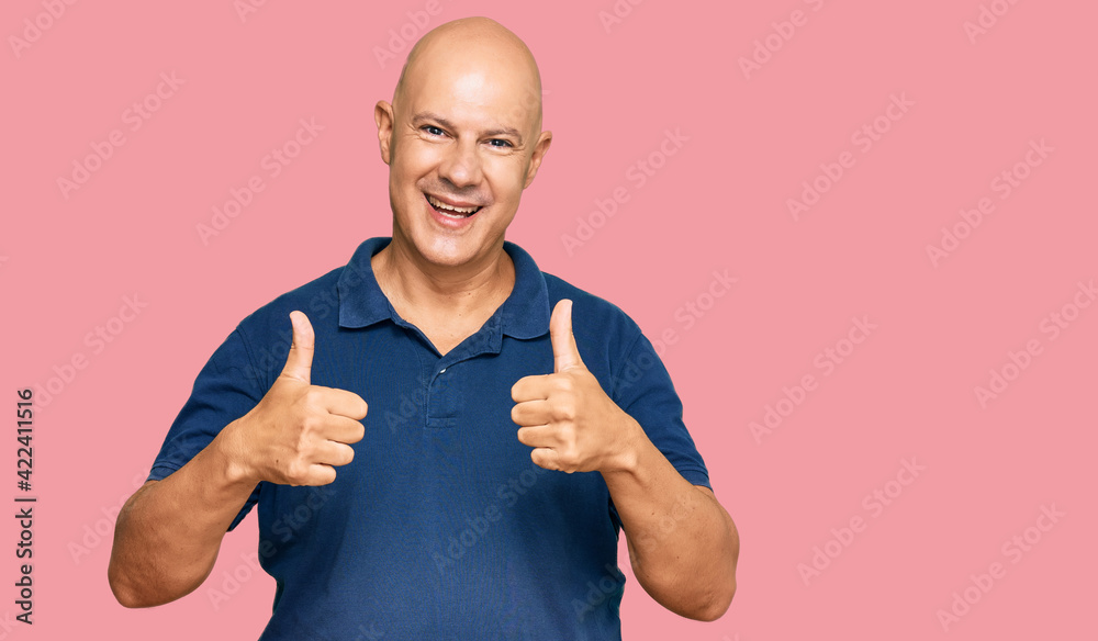 Wall mural middle age bald man wearing casual clothes success sign doing positive gesture with hand, thumbs up 