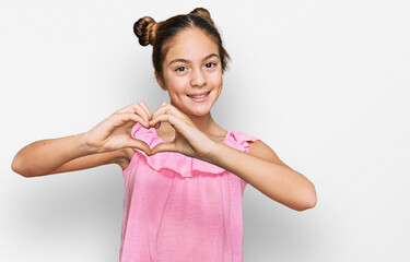 Beautiful brunette little girl wearing summer pink shirt smiling in love showing heart symbol and shape with hands. romantic concept.