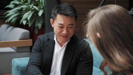 Startup investment confirmation meeting between asian investor and caucasian female startupper businesswoman colleagues shaking hands wearing casual formal business clothing in modern office workplace - Powered by Adobe
