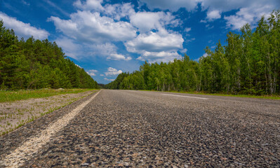Highway in the forest against the background of the sky..