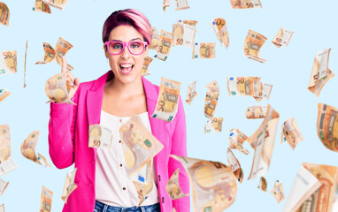 Young beautiful woman with pink hair wearing business jacket and glasses pointing finger up with successful idea. exited and happy. number one.