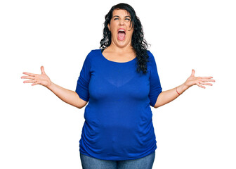 Plus size brunette woman wearing casual clothes crazy and mad shouting and yelling with aggressive expression and arms raised. frustration concept.