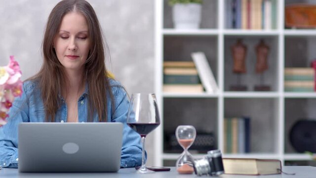 Woman working online with laptop computer at home sitting at desk. Businesswoman in office, browsing internet, blogger reading writing.