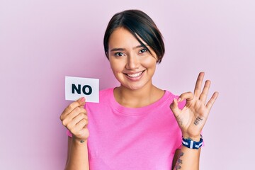 Beautiful young woman with short hair holding no word message doing ok sign with fingers, smiling friendly gesturing excellent symbol