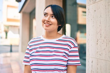 Young latin girl smiling happy walking at the city.