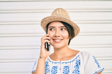 Young latin tourist girl on vacation smiling happy talking on the smartphone at the city.