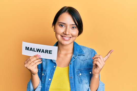 Beautiful young woman with short hair holding malware paper smiling happy pointing with hand and finger to the side