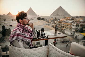 Young man overlooking the pyramids of Giza - obrazy, fototapety, plakaty