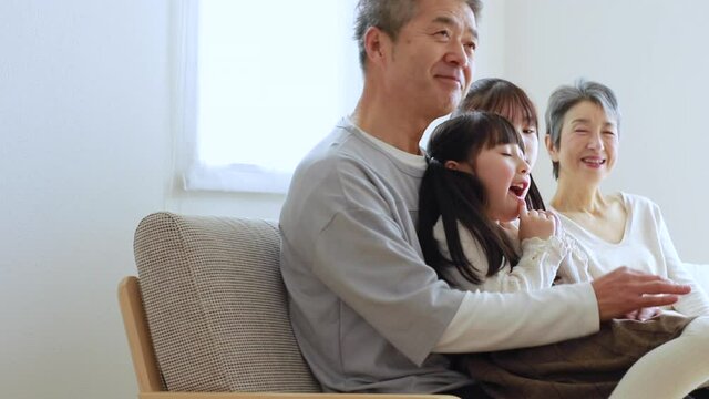 ソファに座りくつろぐ日本人シニア夫婦と孫