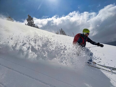 freerider skier drives through the powder snow down the mountain. Joy in life. Adventure in the swiss mountains. Glarus