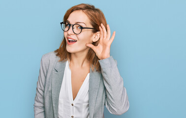 Young caucasian woman wearing business style and glasses smiling with hand over ear listening an hearing to rumor or gossip. deafness concept.