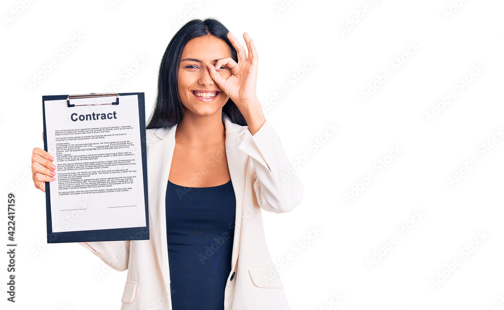 Canvas Prints Young beautiful latin girl holding clipboard with contract document smiling happy doing ok sign with hand on eye looking through fingers