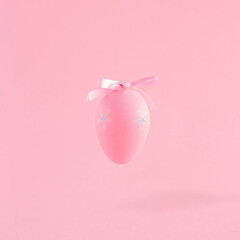 Creative composition with pink Easter egg and bow. Minimal spring Holiday concept. Pastel background.