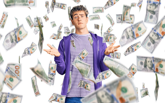 Young handsome man wearing casual purple sweatshirt clueless and confused expression with arms and hands raised. doubt concept.