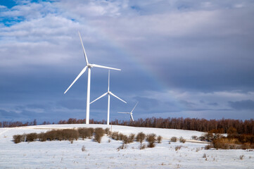 Rainbow over wind turbine in winter - 422418550