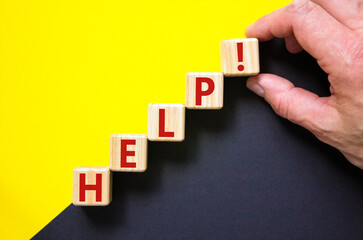 Support and help symbol. Wooden cubes with the word 'help'. Businessman hand. Business, psychology, support and help concept. Beautiful yellow and black background, copy space.