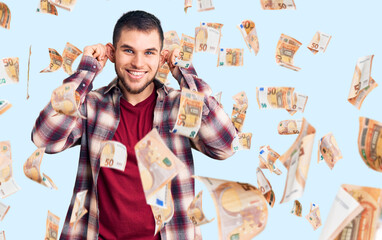 Young handsome man wearing casual shirt smiling pulling ears with fingers, funny gesture. audition...