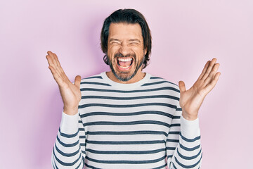 Fototapeta premium Middle age caucasian man wearing casual clothes celebrating mad and crazy for success with arms raised and closed eyes screaming excited. winner concept