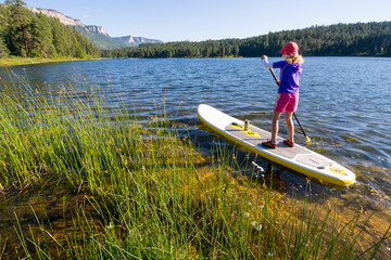 A girl paddle boarding on Haviland Lake, San Juan National Forest, Durango, Colorado.