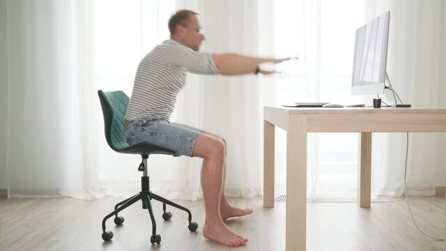 Middle-aged writer man in eyeglasses rotating on swivel chair and thinking about narrative then typing down in using PC keyboard. Novelist freelance on worldwide quarantine time 4K video concept 