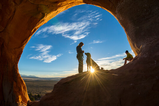 A mother and daughter standing at sunset in the Looking Glass Arch, La Sal, Utah.