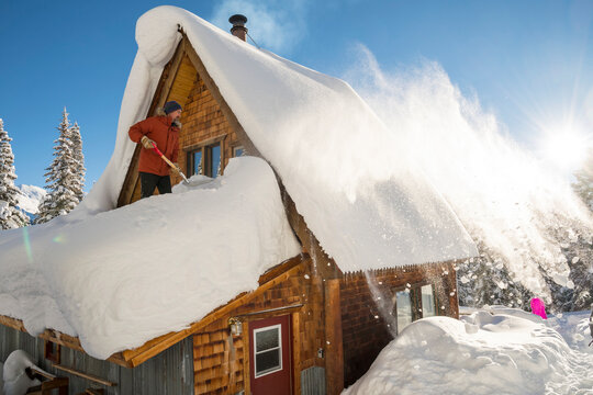 A man shovelling the roof of the Aladdin's Lamp Hut, Molas Pass, Silverton, Colorado.