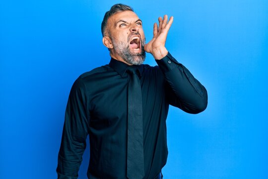 Middle age handsome man wearing business shirt and tie shouting and screaming loud to side with hand on mouth. communication concept.