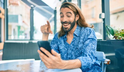 Young middle eastern man doing video call using smartphone at coffee shop.