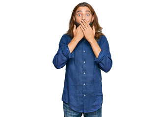 Attractive man with long hair and beard wearing casual clothes shocked covering mouth with hands for mistake. secret concept.