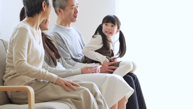 ソファに座りくつろぐ日本人シニア夫婦と孫