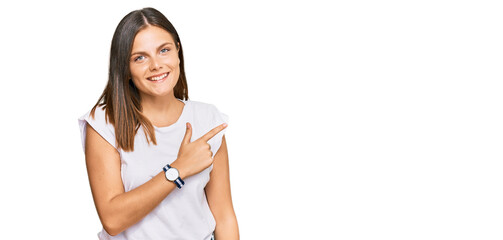 Young caucasian woman wearing casual white tshirt cheerful with a smile of face pointing with hand and finger up to the side with happy and natural expression on face