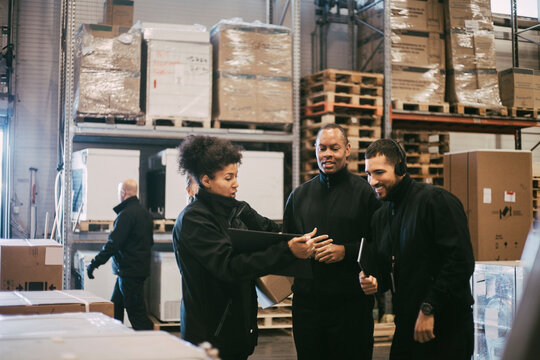 Businesswoman explaining colleagues during meeting in logistics warehouse