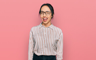 Young hispanic girl wearing casual clothes and glasses winking looking at the camera with sexy...