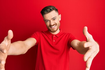 Fototapeta premium Young redhead man wearing casual clothes looking at the camera smiling with open arms for hug. cheerful expression embracing happiness.