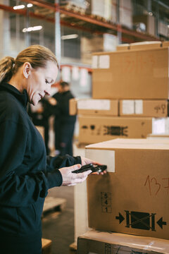 Female entrepreneur scanning with bar code reader at logistics warehouse