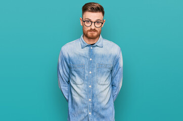 Young redhead man wearing casual denim shirt skeptic and nervous, frowning upset because of problem. negative person.