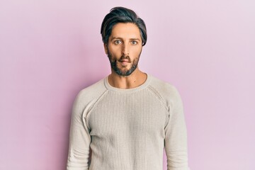 Fototapeta premium Young hispanic man wearing casual winter sweater making fish face with lips, crazy and comical gesture. funny expression.