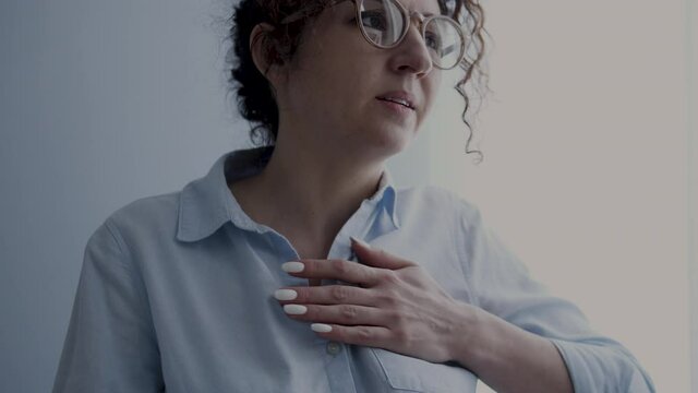 Woman touching her chest feeling pain and hardly breathing, risk of heart attack